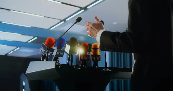 stock image Dolly shot of male organization representative pronouncing speech from the tribune during press campaign in the conference hall. Politician answers questions, gives interview for television or media.