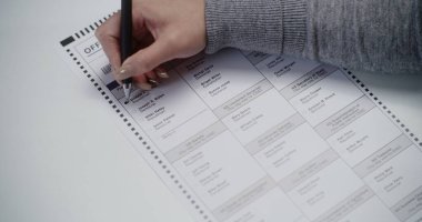 ZAPORIZHYA, UKRAINE - 15 Mart 2024: Oy verme kabininde oy pusulası dolduran anonim Amerikan vatandaşının kapanışı. Kadın oy kullanma merkezinde Donald Trump 'a oy veriyor. Ulusal Seçim Günü
