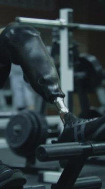 Modern fitness merkezinde bacak trenleri üzerinde protezi olan sporcuların dikey çekimi. Fiziksel engelli yetişkin bir sporcu profesyonel spor salonunu kullanarak antrenman yapıyor.