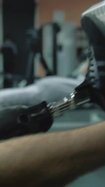 Modern spor salonunda protez bacaklı sporcunun bacak pres makinesi üzerinde egzersiz yaparken dikey çekimi. Fiziksel engelli atletik bir adam profesyonel spor ekipmanları kullanarak antrenman yapıyor.