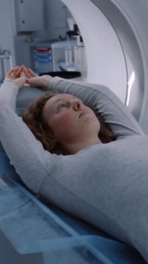 MRI veya CT tarama prosedürünün dikey görüntüsü, makinenin içindeki yatakta yatıyor. Kadın hastaların beyin ve vücut taramalarının VFX animasyonu. Modern tıp laboratuarında geliştirilmiş gerçeklik ekipmanı