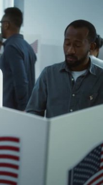 Afro-Amerikalı bir adamın dikey çekimi, oy kullanma merkezindeki kabinde yapılmaya başlandı. Birleşik Devletler 'de Ulusal Seçim Günü. ABD başkan adaylarının siyasi ırkları. Vatandaşlık görevi. Yavaş