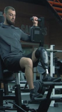 Modern fitness merkezinde protez bacak egzersizleri yapan dikey şutçu adam. Fiziksel engelli motive bir sporcu profesyonel spor ekipmanları kullanarak güçlü bir antrenman yapıyor..