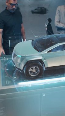 İki erkek otomotiv tasarımcısı, yeni elektrikli arabanın gövdesini fütüristik sanal gerçeklik holografik otomobil modeliyle yaratıyor. Aracın gelişmiş teknolojisinin 3 boyutlu görselleştirilmesi. Dikey çekim