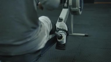 Modern spor salonunda ya da fitness merkezinde kürek çekme makinesi üzerinde protez bacak egzersizi yapan atletik bir adam. Fiziksel engelli motive bir sporcu profesyonel spor ekipmanları kullanarak güçlü bir antrenman yapıyor..