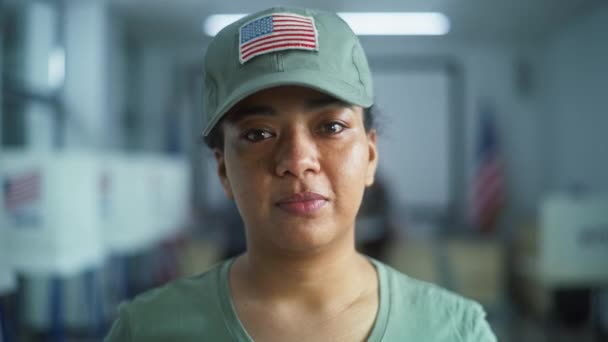 女性兵士の肖像画 アメリカ合衆国選挙の有権者 カモフラージュのユニフォームの女性は ポーリングステーションに立って カメラを見ています 投票ブースの背景 市民の義務に関する概念 — ストック動画