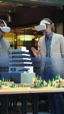 Erkek mimar sanal gerçeklikteki modern yüksek teknoloji binasını ve park mimari projesini meslektaşlarına sunar. Üç boyutlu hologram. Dikey çekim