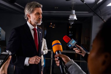 Ciddi Amerikalı erkek politikacı gazetecilerle konuşuyor, soruları cevaplıyor ve hükümet binasında medya ve televizyon haberleri için röportaj veriyor. Basın toplantısı sırasında Birleşik Devletler Kongre Üyesi.