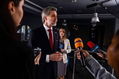 Ciddi Amerikalı erkek politikacı gazetecilerle konuşuyor, soruları cevaplıyor ve hükümet binasında medya ve televizyon haberleri için röportaj veriyor. Basın toplantısı sırasında Birleşik Devletler Kongre Üyesi.