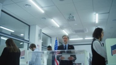 Olgun ABD 'li işadamı veya politikacı oy pusulasını sandığa koydu. Basın, oy verdikten sonra adamın fotoğrafını çekiyor. Çeşitli Amerikan halkı oy kullanma merkezindeki kabinlerde oy kullanıyor. Amerika Birleşik Devletleri Seçim Günü.
