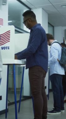 Çoklu etnik Amerikan vatandaşlarının oy kullanma merkezindeki kabinlerde dikey çekimleri. Birleşik Devletler 'de Ulusal Seçim Günü. ABD başkan adaylarının siyasi ırkları. Vatandaşlık görevi. Yavaş