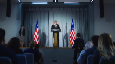 Amerikan cumhuriyetçi politikacı basın toplantısında destekçilerine başarılı bir konuşma yaptı. ABD Başkanı gazetecilerin sorularını yanıtlıyor, röportaj veriyor. Amerikan bayraklı arka plan. Dolly vurdu..