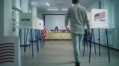 Afro-Amerikalı erkek seçmen kayıt masasına yürür, oy pusulasına gider. Amerikan bayrağı logosu olan oy kullanma yerleri ve oy kullanma çağrısı. Amerika Birleşik Devletleri Seçim Günü.
