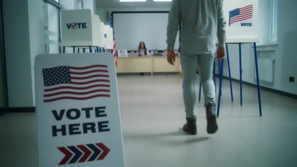 アフリカ系アメリカ人男性 男性有権者は 投票所で登録のための女性投票官に歩き 投票のための紙投票を取ります アメリカ合衆国の国民選挙の日 市民としての義務 — ストック動画