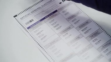 ZAPORIZHYA, UKRAINE - 15 Mart 2024: Oy verme kabininde anonim erkek ABD vatandaşının kağıt bültenini doldurması. Oy kullanma merkezindeki Afrikalı Amerikalı adam Joe Biden 'a oy veriyor. Ulusal Seçimler