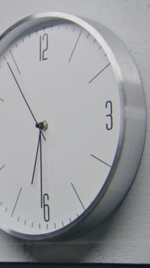 Yürüyen duvar saatlerinin modern tasarımla statik görüntüsü. Duvarda birden fazla beyaz saat asılı ve farklı zaman dilimlerini gösteriyor. Çalışan zaman göstergelerine sahip katı saatler. Dikey