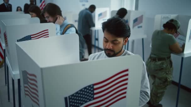 インド人男性 アメリカ市民が投票所のブースで投票 アメリカ合衆国の国民選挙の日 アメリカ合衆国大統領候補の政治的競争 市民の義務と愛国心 ドリー ショット — ストック動画