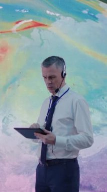 Küresel ısınma sorununu araştırırken orta yaşlı bir adamın tablet kullanırken ve çalışanlarla konuşurken çekilmiş dikey bir fotoğrafı.