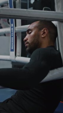 Yorgun ve yorgun Afrikalı Amerikalı boksör boks ringinin köşesinde oturuyor. Yüzünde boncuk boncuk ter olan dövüşçü antrenmandan sonra dinleniyor. Sporcu boks salonunda turnuvaya ya da yarışmaya hazırlanıyor. Dikey