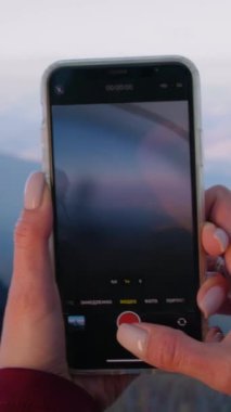 Kadın, güzel bir dağ manzarasında telefon kullanarak yürüyüşçünün resmini çekiyor. Elinde balta olan Afrikalı Amerikalı turist tepede poz veriyor. Gezginler macera tatili sırasında dinlenmek için durdular. Dikey çekim