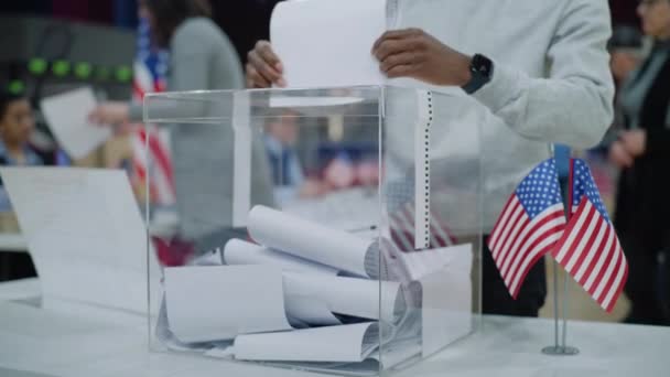 ポーリングステーションのテーブルの上に立っている投票箱の近くのショット アメリカの有権者が来て 弾丸を箱に入れた アメリカ合衆国大統領候補の政治的競争 アメリカ合衆国選挙の日 — ストック動画