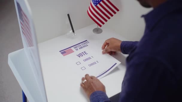 アフリカ系アメリカ人の男性有権者は投票所で投票ブースに来て 選択し 紙投票を記入する アメリカ合衆国の国民投票の日に米国市民 市民としての義務 — ストック動画