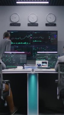 Çoklu etnik gruptan tüccarlar, gerçek zamanlı sergilenen çoklu monitörlü bilgisayarlar üzerinde çalışıyorlar. Meslektaşlar büyük ekranlarda döviz piyasalarının grafiklerini analiz ederler. Kripto para ticareti ve yatırım. Dikey