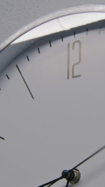 Duvarında metal çerçeve asılı beyaz saatin statik görüntüsü ve zamanı gösteriyor. Modern tasarımla ofiste yürüyen duvar saati. Hızlı çalışan zaman göstergesine sahip katı bir saat. Zaman ayarlı. Dikey