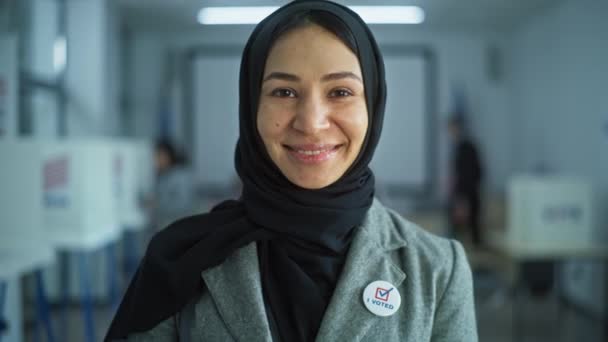 アラビア女性の肖像画 アメリカ合衆国選挙の有権者 女性は現代の投票所に立って ポーズ そしてカメラを見ています 投票ブースの背景 市民の義務に関する概念 — ストック動画