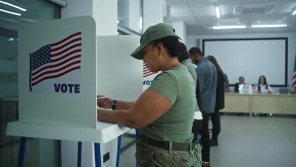 アメリカ陸軍の女性兵士が投票所でブースに投票 アメリカ合衆国の国民選挙の日 アメリカ合衆国大統領候補の政治的競争 愛国心と市民の義務 ドリー ショット — ストック動画