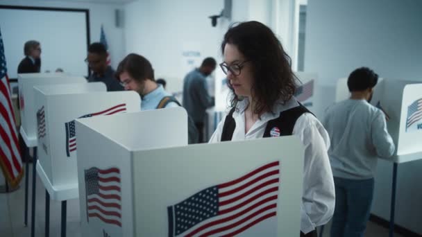 メガネの女性が投票所のブースで投票します アメリカ合衆国選挙の日 アメリカ合衆国大統領候補の政治的競争 市民の義務と愛国心 スローモーション ドリー ショット — ストック動画