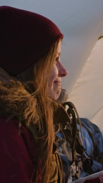 年轻的女游客和丈夫坐在山顶的帐篷里 白人女人手里拿着杯子 看着夕阳 与非裔美国男人交谈 一对夫妇在山上度假 — 图库视频影像