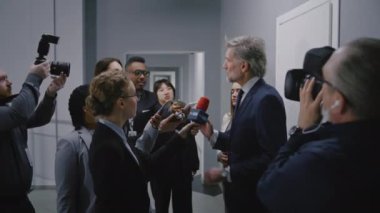 Kızgın AB konsolosu basın sorularını yanıtlıyor, hükümet binası koridorunda medya için röportaj veriyor. Avrupa Birliği Temsilcisi TV haber muhabirleri kalabalığıyla çevrili. Basın kampanyası.