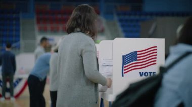 Elinde bültenle Afrika kökenli Amerikalı seçmen oy verme kabinine geliyor. Çeşitli Amerikan vatandaşları oy kullanma merkezine oy vermeye geldi. ABD başkan adaylarının siyasi ırkları. Ulusal Seçim Günü.