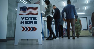 Vote here sign on the floor. Multi ethnic American citizens vote in booths in polling station office. National Election Day in United States. Political races of US presidential candidates. Civic duty. clipart