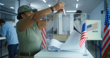 Çok ırklı seçmenler ya da Amerikan halkı oy kullanma merkezindeki kabinlerde oy kullanıyor. Asyalı kadın ve Afro-Amerikan kadın ordusu ilan kutusuna koydu. Birleşik Devletler 'de Ulusal Seçim Günü. Yurttaşlık görevi.
