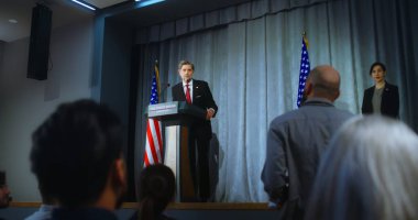 ABD başkan adayı kampanya konuşması yapıyor, soruları cevaplıyor, röportaj veriyor. Amerikalı cumhuriyetçi politikacı basınla yaptığı görüşmede performans sergiliyor. Seçim günü. Amerikan bayraklı arkaplan.