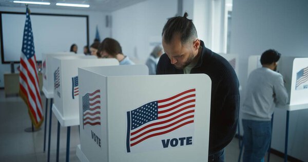 Мужчина приходит голосовать в кабинке в избирательном участке. Национальный день выборов в США. Политические гонки кандидатов в президенты США. Концепция гражданского долга и патриотизма. Долли выстрелил.