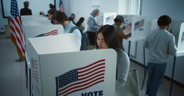 stock image Asian woman comes to vote in booth in polling station office. National Election Day in the United States. Political races of US presidential candidates. Concept of civic duty. Slow motion. Dolly shot.