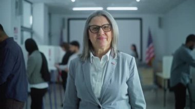 Yetişkin kadın portresi, Amerika Birleşik Devletleri seçmeni. İş kadını modern bir seçim merkezinde duruyor, poz veriyor ve kameraya bakıyor. Oy verme kabinleri olan bir arka plan. Yurttaşlık görevi kavramı.