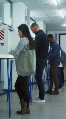 Çeşitli Amerikan vatandaşlarının sandık merkezindeki kabinlerde dikey çekimleri. Birleşik Devletler 'de Ulusal Seçim Günü. ABD başkan adaylarının siyasi ırkları. Vatandaşlık görevi. Yavaş