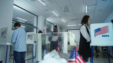 Çok ırklı seçmenler ve ABD vatandaşları sandık merkezindeki oy kullanma kabinlerinde müstakbel cumhurbaşkanına oy veriyorlar. Afro-Amerikalı adam oy pusulasını kutuya koydu. Amerika Birleşik Devletleri Ulusal Seçim Günü.