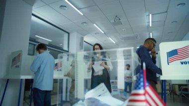 Çok ırklı seçmenler, Amerikan vatandaşları oy kullanma merkezindeki oy kullanma kabinlerinde geleceğin başkanına oy veriyorlar. Beyaz kadın ilan kutusuna koyuyor. Amerika Birleşik Devletleri 'nde Seçim Günü. Yavaş çekim.