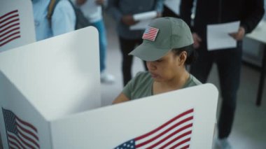 Modern oy kullanma merkezindeki kabinde kadın Amerikan askeri oy kullanıyor. Birleşik Devletler 'de Ulusal Seçim Günü. ABD başkan adaylarının siyasi ırkları. Vatandaşlık görevi ve vatanseverlik kavramı.