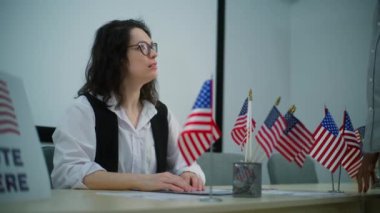 Kadın anket memuru oy kullanma merkezindeki kayıt masasında oturuyor, Afrikalı Amerikalı adamla konuşuyor ve kağıt oyları veriyor. Birleşik Devletler 'de Ulusal Seçim Günü. Vatandaşlık görevi ve vatanseverlik.