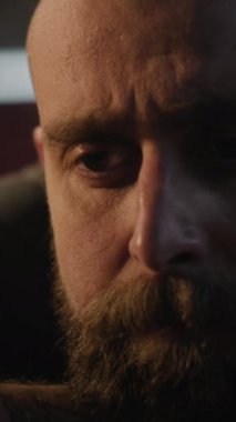 Kafkasyalı dövmeli zanaatkârın yakın çekim masasında oturup karanlık atölyede metronoma bakması. Profesyonel orta yaşlı zanaatkar uzun bir iş gününden sonra dinlenir. El yapımı ve girişimcilik kavramı.