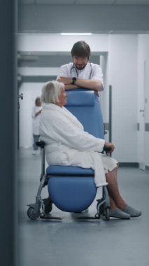 Erkek doktor, klinik koridorunda tekerlekli sandalyedeki kadın hastayla birlikte duruyor. Ameliyathane yakınındaki ameliyattan önce doktor yaşlı bir kadınla konuşur. Sağlık personeli, hastanedeki ya da sağlık merkezindeki hastalar.