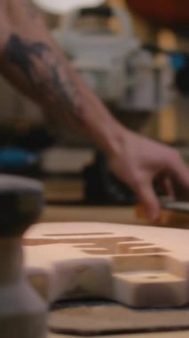 Erkek marangozun cila çektikten sonra gitar yakasına yaptığı yakın çekim. Ahşap ustası, zanaatkar modern atölyede müzik aleti yapıyor. Dikey çekim