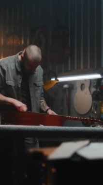 Profesyonel erkek marangoz akustik gitar ve telleri paçavrayla siler. Ahşap işçiliği, ahşap müzik aleti yapar, modern atölyede iş arkadaşıyla çalışır. El yapımı ve girişimcilik..