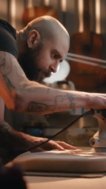 Profesyonel erkek zanaatkar öğütme makinesi kullanarak tahta gitar gövdesini öğütüyor. Ahşap ustası, marangoz modern atölyede müzik aleti yapıyor. Dikey çekim